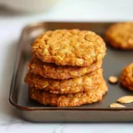 Soft golden-brown Finger Food Pumpkin Cookies for Babies, with visible oats, stacked neatly on a baking tray, crisp edges and a chewy, moist appearance.