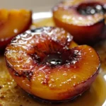 Glazed honey balsamic baked peaches with a golden caramelized surface and juicy centers, served on a white plate, showcasing shiny syrup and vibrant color for a stunning dessert presentation.