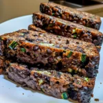Moist slices of Keto Zucchini Bread studded with chocolate chips and green zucchini flecks, artfully arranged on a white plate for an inviting, low-carb breakfast.