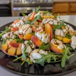 Colorful Peach Burrata Salad with juicy peach slices, creamy burrata cheese, arugula, basil, and balsamic glaze on a black plate, fresh and vibrant for summer enjoyment