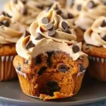 Golden pumpkin chocolate chip cupcakes with fluffy cinnamon buttercream frosting, decorated with semi-sweet chocolate chips and a moist, rich interior.
