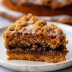 Golden vegan pumpkin coffee cake with a thick crumbly cinnamon streusel topping and light glaze served on a white plate