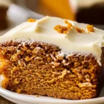 Golden orange 3-Ingredient Pumpkin Spice Cake slice with creamy white frosting on top, served on a white plate, showing moist crumb and festive presentation.