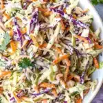 Vibrant healthy coleslaw with Greek yogurt, featuring shredded green and red cabbage, carrot, and fresh parsley in a creamy dressing, beautifully arranged in a white bowl.