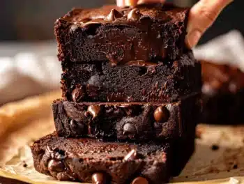 Moist Chocolate Pumpkin Bread with melty chocolate chips, deep brown color, and a glossy, rich texture stacked in thick, tempting slices on parchment paper.