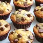 Close-up of moist banana chocolate chip muffins with golden tops and melted chocolate chips.