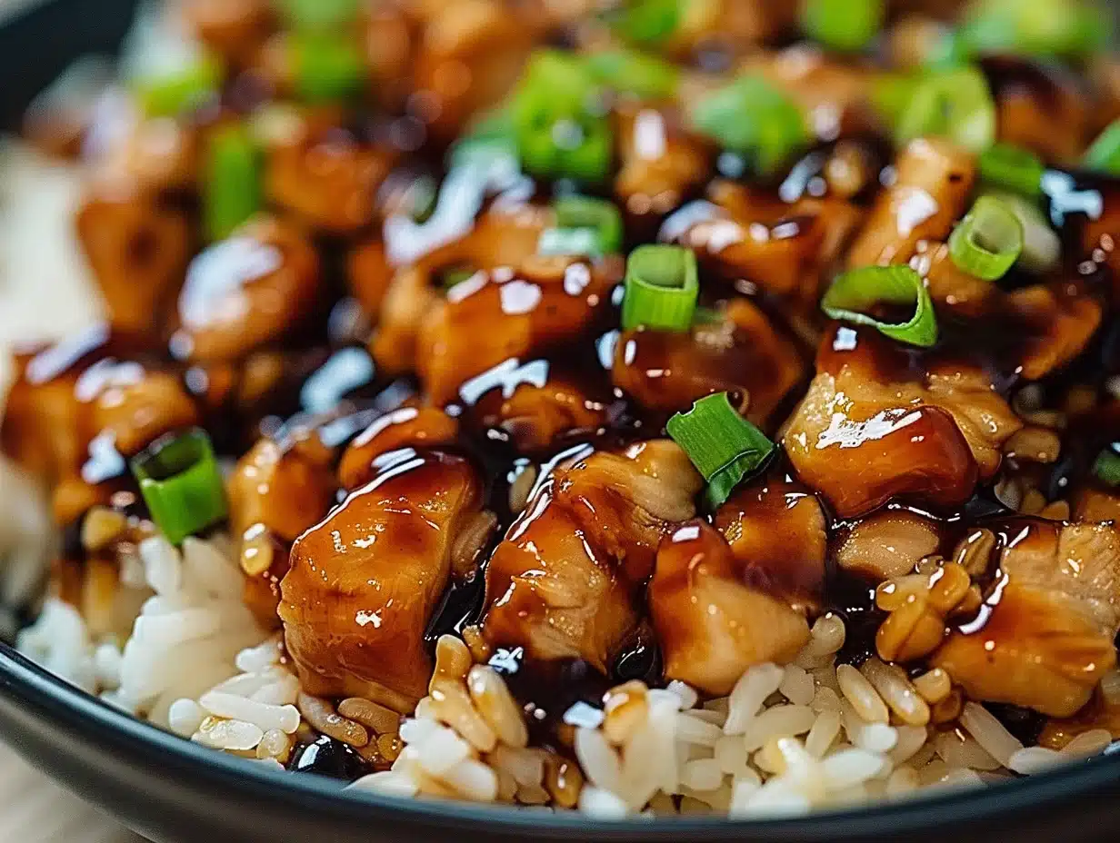 Close-up of Honey BBQ Chicken Rice with glossy sauce, vibrant green onions, and fluffy rice in a dark bowl.