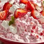 Close-up of creamy, fluffy strawberry fluff salad dessert with fresh strawberry slices and marshmallows in bowl