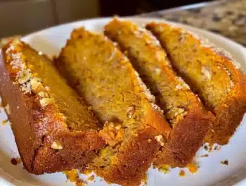 Sliced Classic Spiced Pumpkin Bread on a white plate showcasing warm spices and moist texture