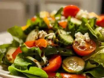 Close-up of vibrant Garden Fresh Mixed Salad with cherry tomatoes, cucumbers, bell pepper, red onion, and feta on baby greens with balsamic drizzle.