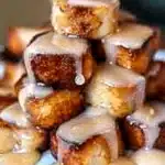 Golden-brown cinnamon roll French toast bites stacked and drizzled with sweet icing, tempting and inviting for a dreamy breakfast.