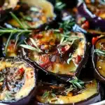 Close-up of golden roasted eggplant slices with herbs and spices, showcasing a vibrant Mediterranean dish