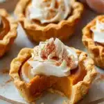 Close-up of mini pumpkin pies topped with whipped cream and sprinkled with cinnamon