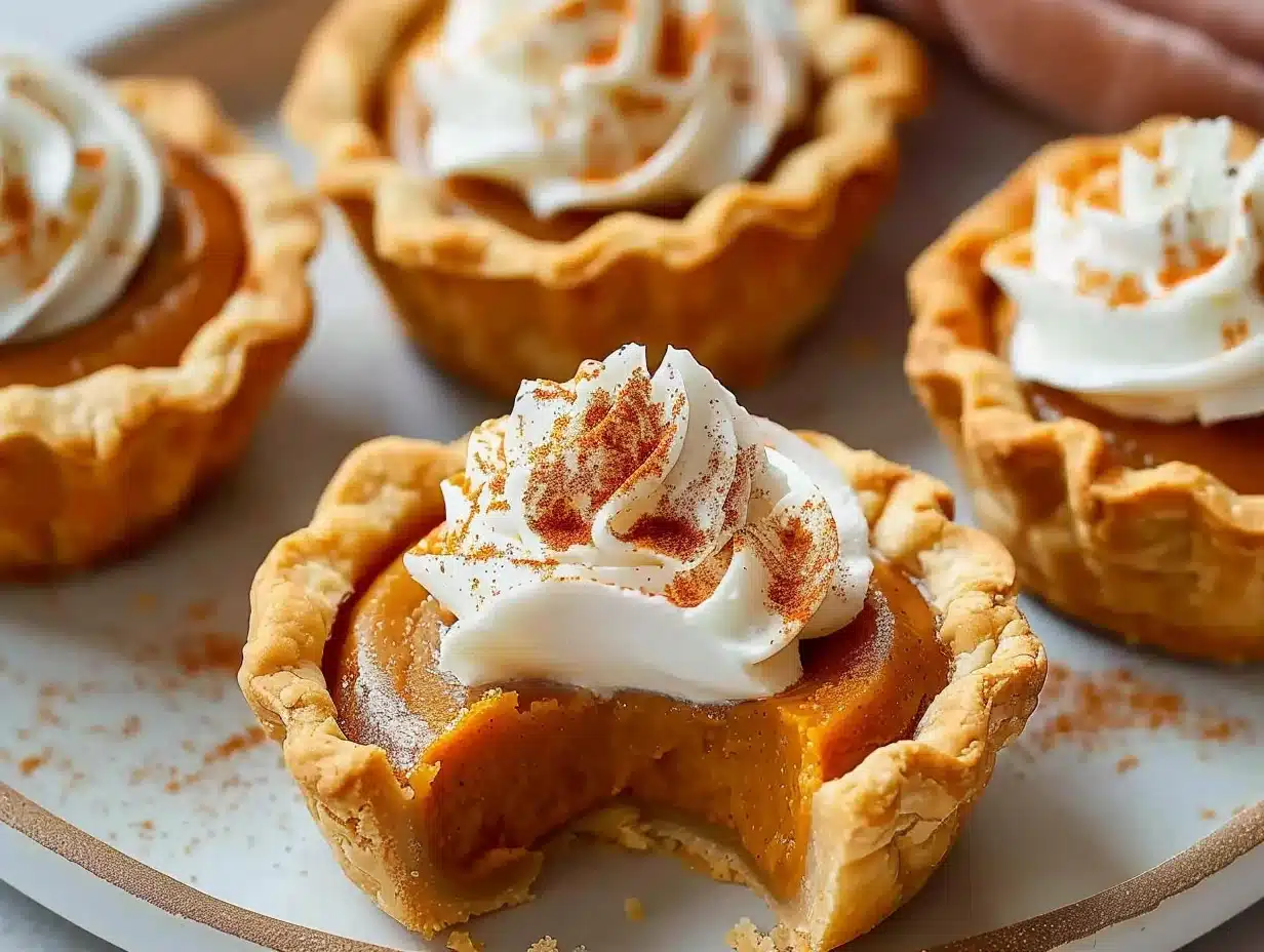 Close-up of mini pumpkin pies topped with whipped cream and sprinkled with cinnamon