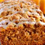 Close-up of pumpkin streusel bread with golden crumb and crumbly streusel topping drizzled with icing, perfect for autumn treats.