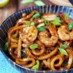 Close-up of delicious Yaki Udon with shrimp garnished with chopped spring onions in a patterned bowl